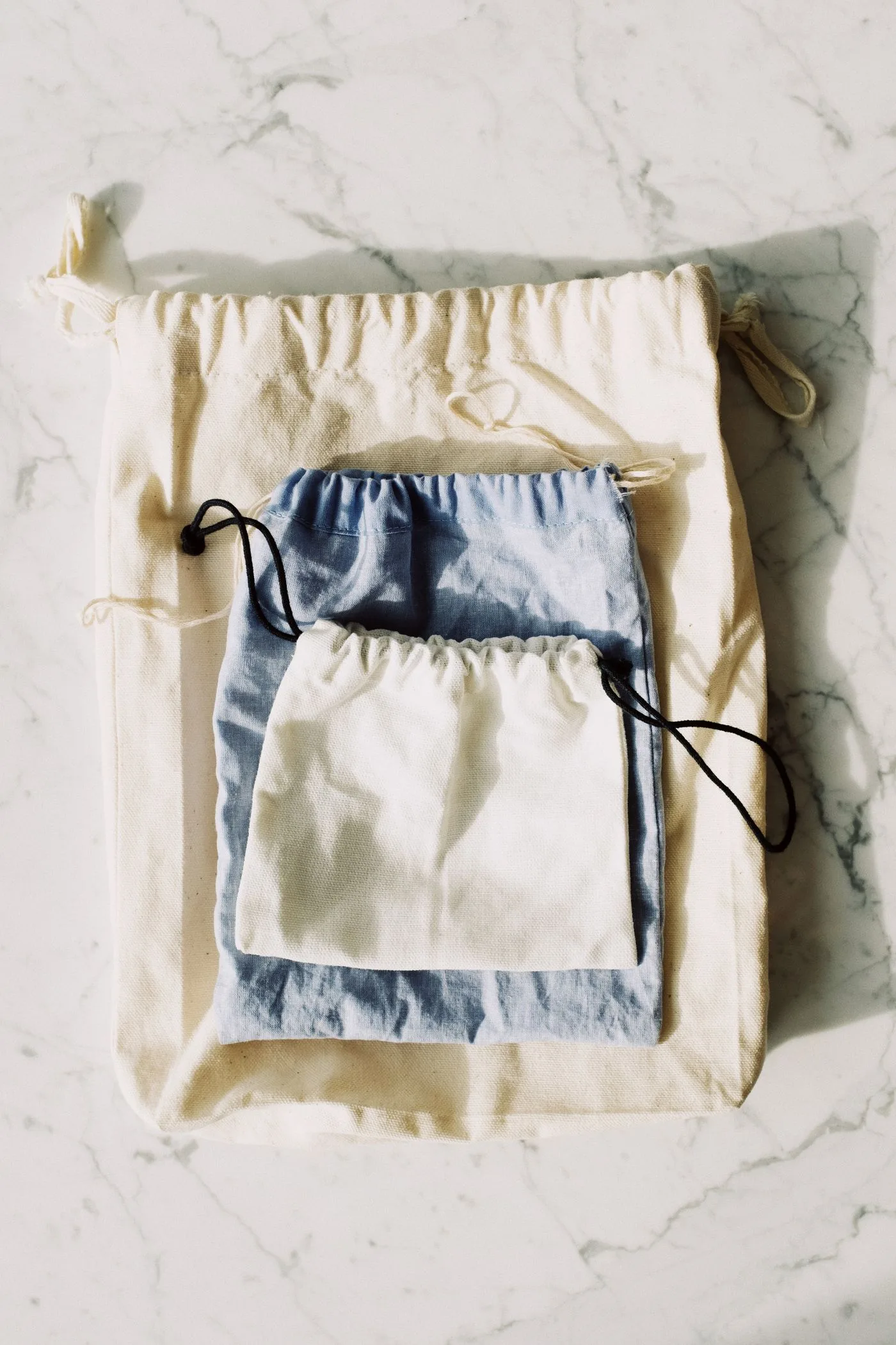 Natural cotton drawstring pouches arranged in soft daylight